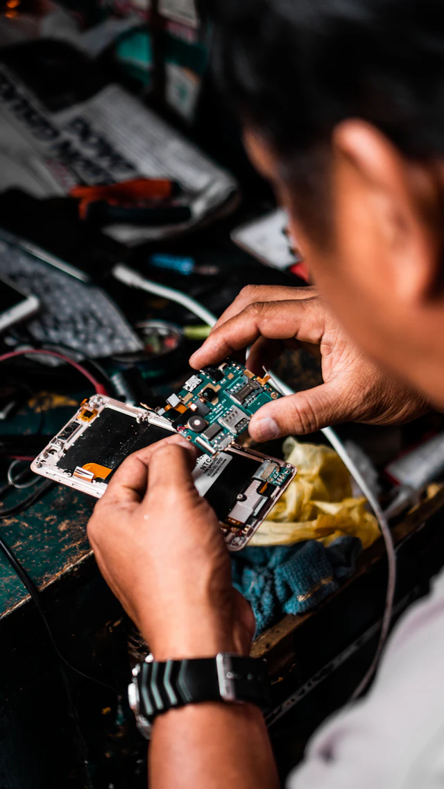 Technician repairing a smartphone circuit board at a workbench