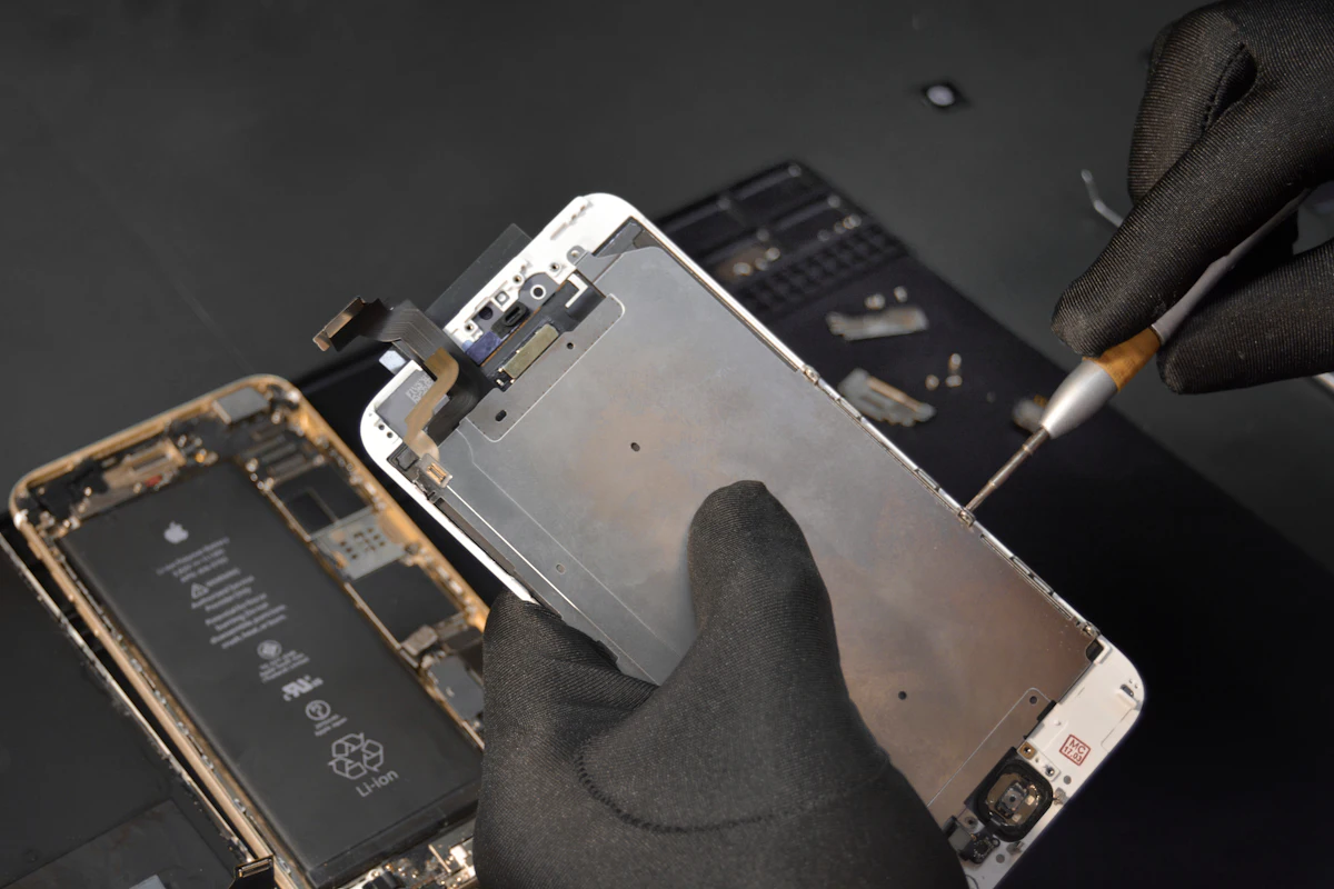 Technician lifting a phone display during a screen replacement